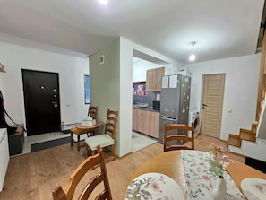 A compact living space with a dining area, kitchen, and a small entryway.