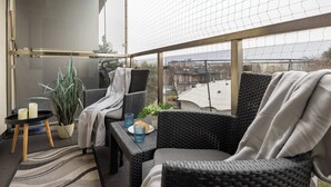 Ein Balkon mit Korbmöbeln, einem Topfpflanzen, Kerzen und einem Teller mit Gebäck.