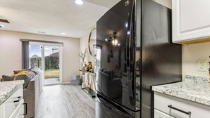Eine moderne Küche mit einem großen, schwarzen Kühlschrank, weißen Schränken und einer Marmorarbeitsplatte.