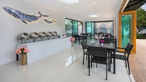 A modern dining area with a long counter, multiple seating arrangements, and decorative wall art. - Amaleena Pool Access, Phuket (Rawai)