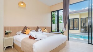 A modern hotel room with a large bed, a bedside table, a lamp, and a view of a swimming pool. - Amaleena Pool Access, Phuket (Rawai)