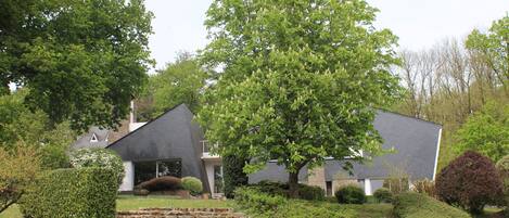 Ein modernes Haus mit grauem Dach, umgeben von gepflegten Rasenflächen und Hecken.