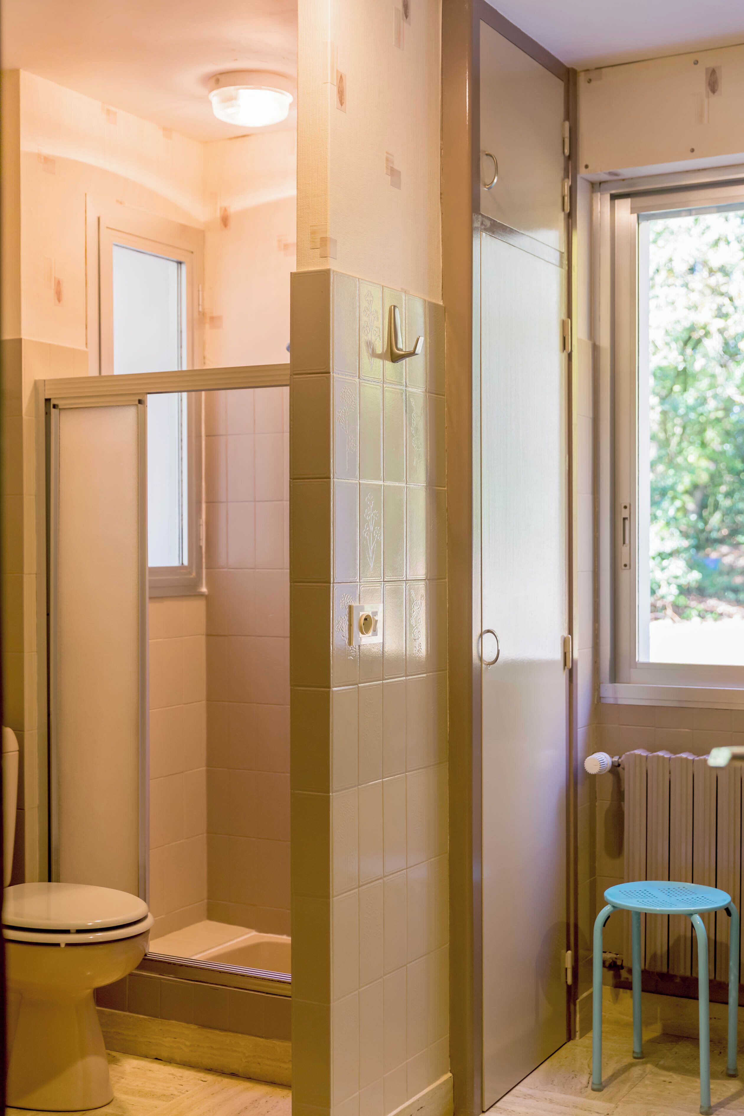 A bathroom with a toilet, a shower, and a window.