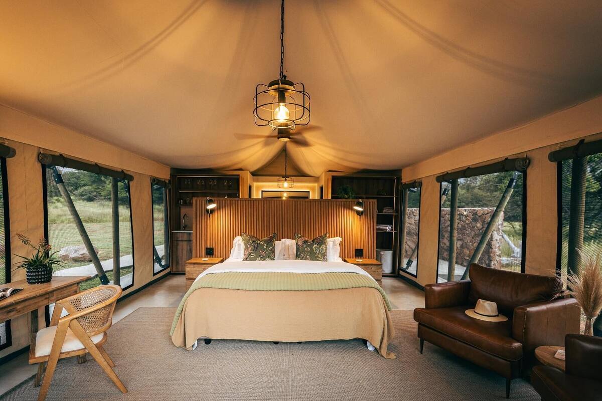 Ein geräumiges Schlafzimmer mit einem großen Bett, einem hölzernen Nachttisch, einem Sessel und einem Tisch mit einer Pflanze.