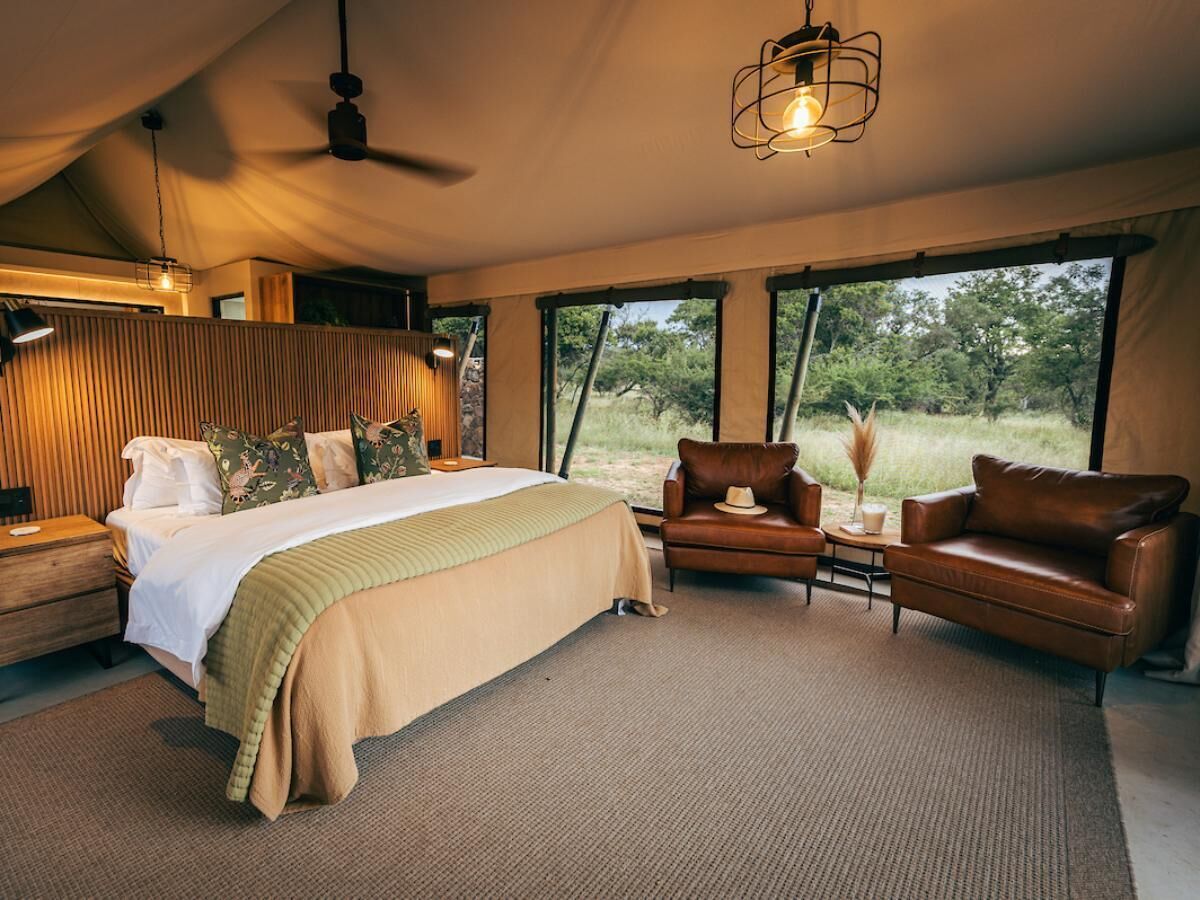 A spacious bedroom with a large bed, a leather sofa, and a view of the outdoors.