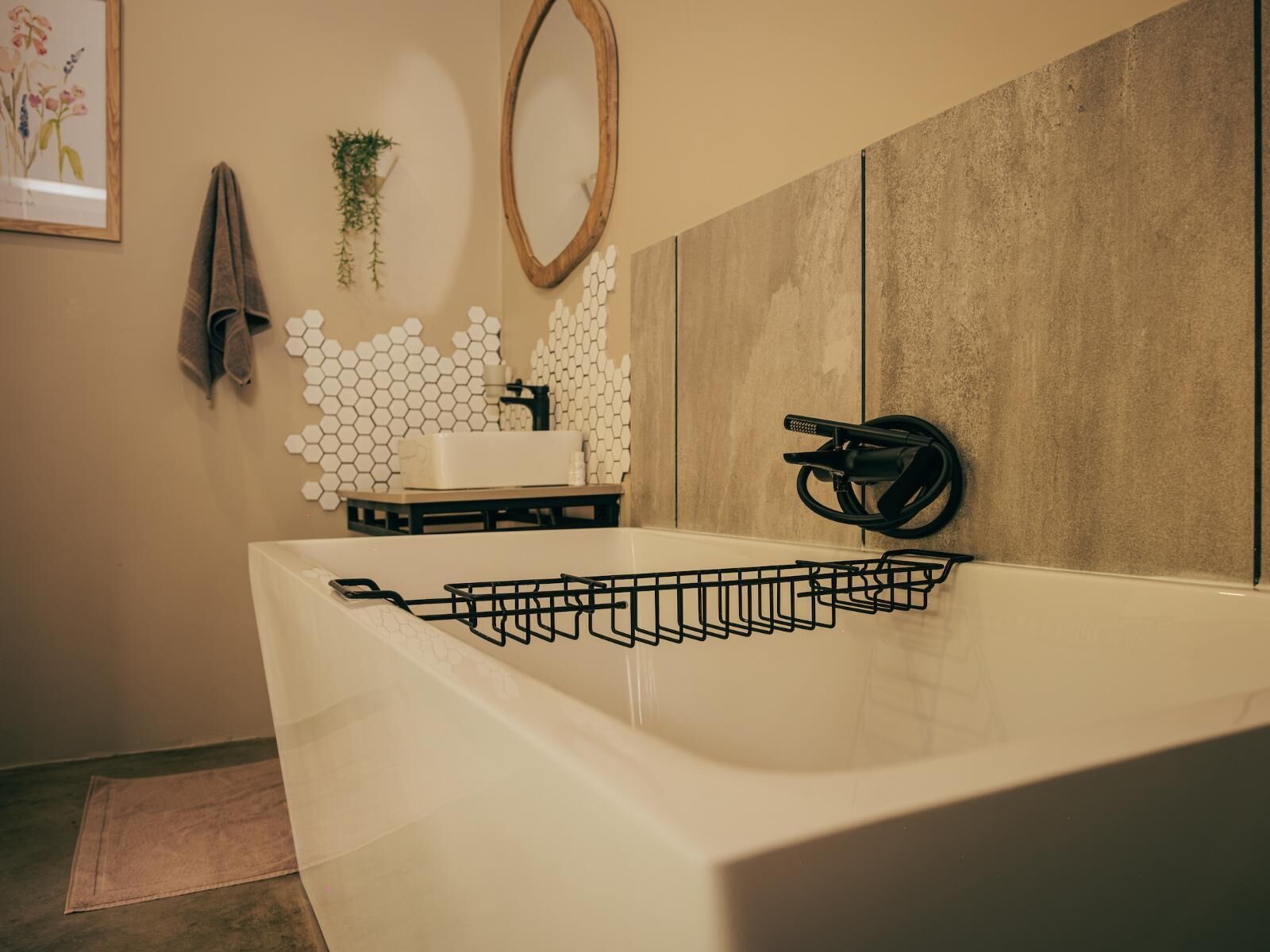 A modern bathroom with a large bathtub, a wooden-framed mirror, a white sink, and a towel rack.