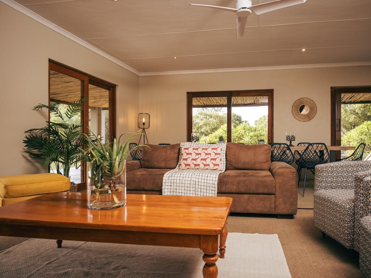 A living room with a brown sofa, a yellow armchair, a wooden coffee table, and a potted plant.