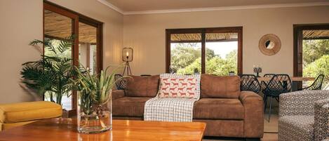 A living room with a brown sofa, a yellow armchair, a wooden coffee table, and a potted plant.