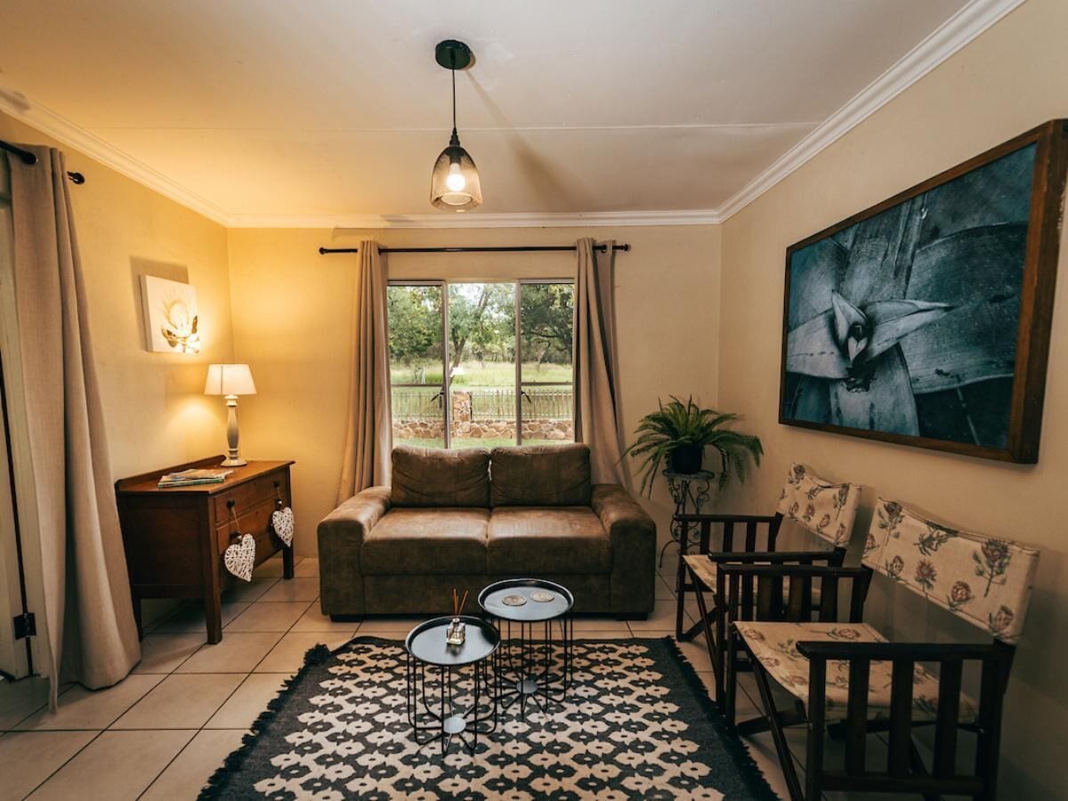 A cozy living room with a sofa, two armchairs, a coffee table, a lamp, and a painting on the wall.