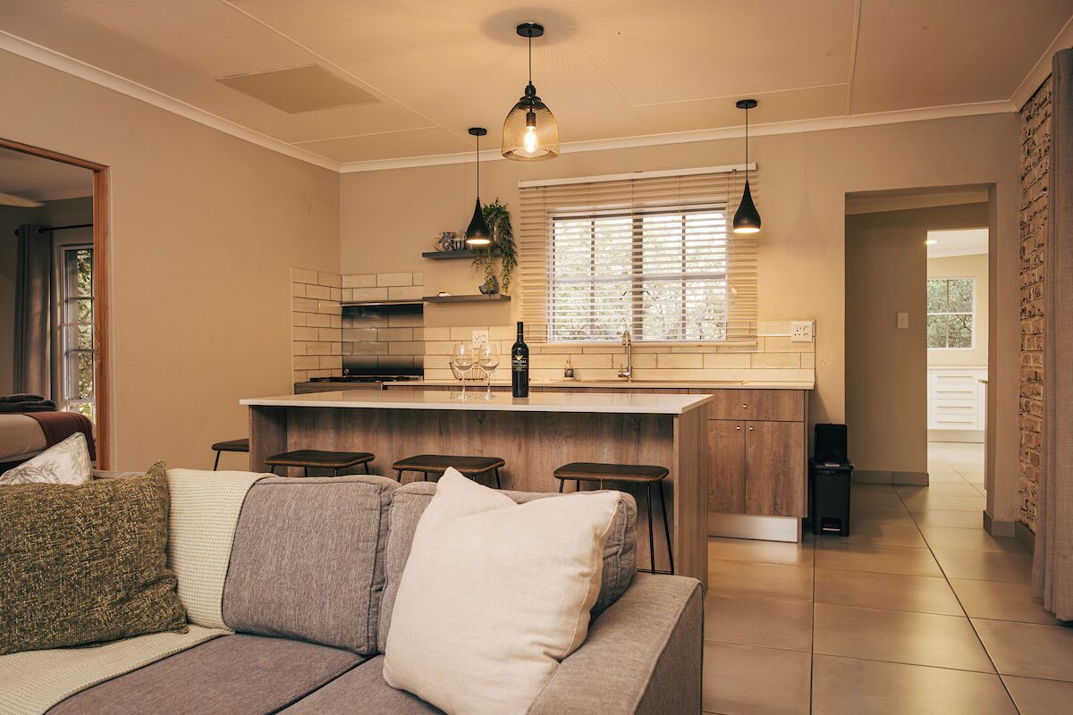 A modern kitchen with a central island, bar stools, pendant lighting, and a view to the dining area.