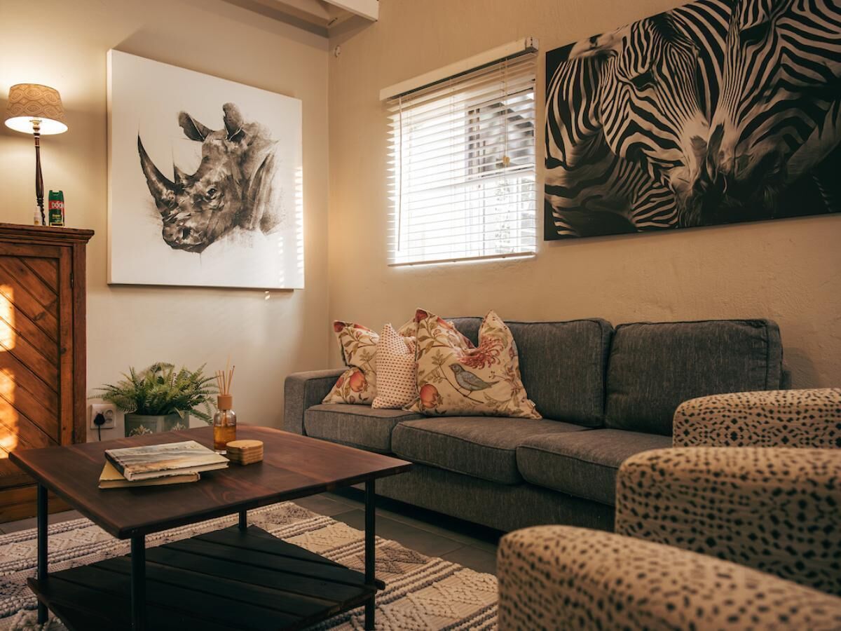 Un salon avec un canapé, une table basse et un tableau représentant un zèbre accroché au mur.