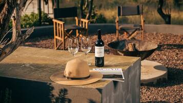 Una mesa de madera con una botella de vino, dos copas y un sombrero de paja.