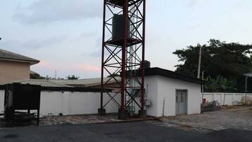 A building with a metal tower structure, a small attached building, and a paved area.