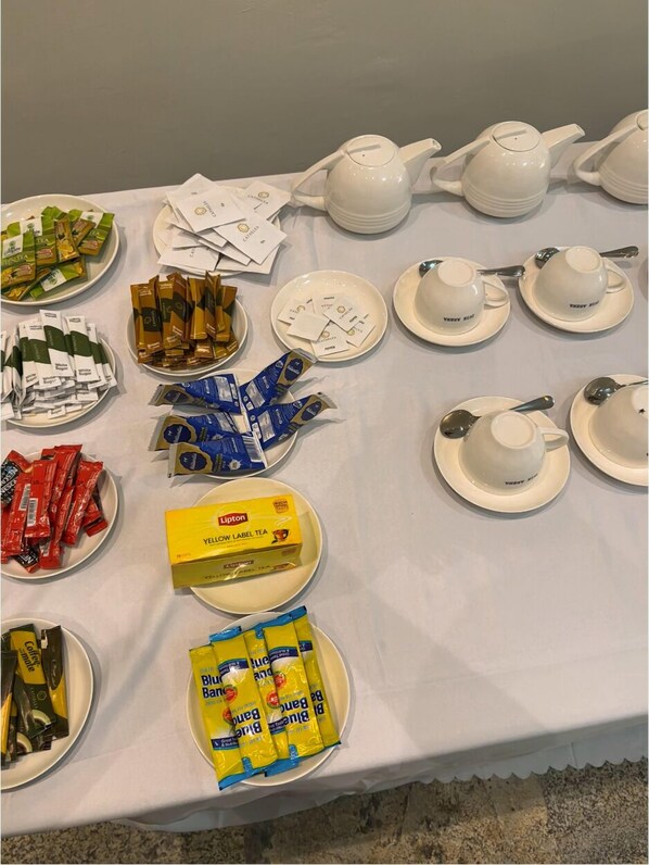 Une table dressée avec différents sachets de thé, des boîtes de thé Lipton, ainsi que des théières et des tasses blanches.