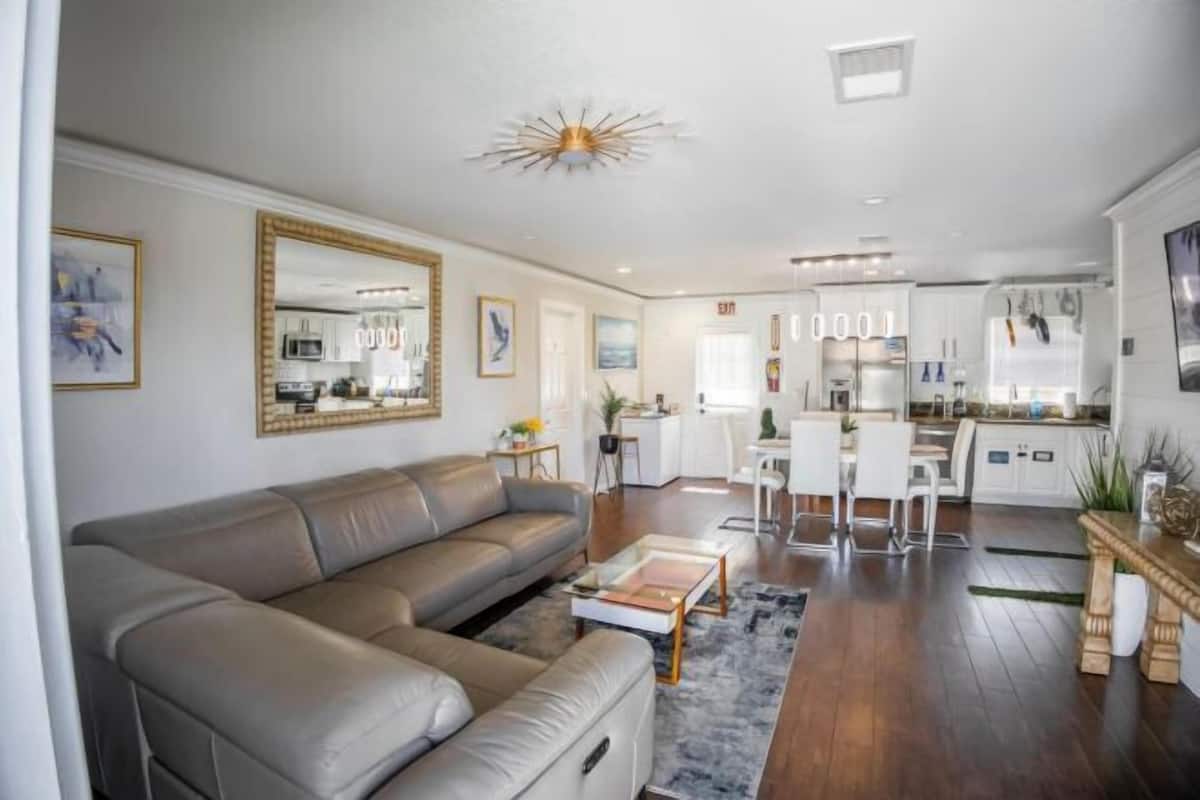A modern living room with a sectional sofa, a coffee table, and a dining area with a white table and chairs.