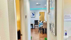 A hallway leading to a dining area with a table and chairs, a television, and artwork on the walls. - Xlnc Exotic Home Sunnyside by sdstay (San Diego)