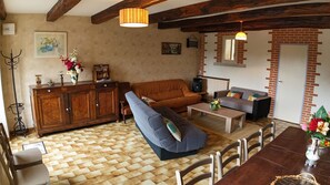 Ein Wohnzimmer mit einer Couch, einem Couchtisch und einem Fernseher. Außerdem ein Holzschrank und ein Kamin.