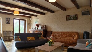 Un salon comprenant un canapé, une table basse et une cheminée. On y trouve également deux fauteuils, un meuble en bois et un tableau accroché au mur.