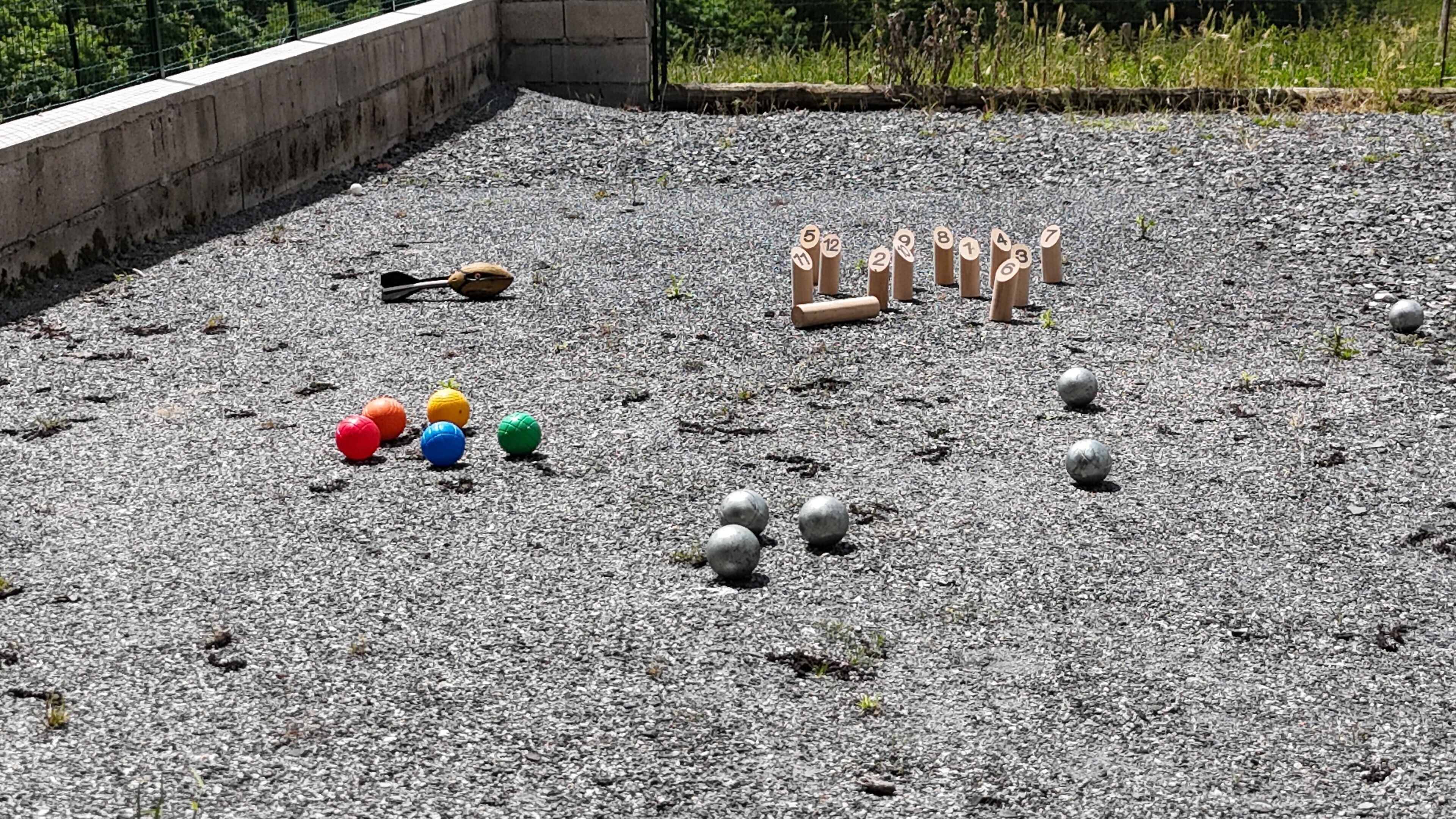 Eine Schotterfläche mit nummerierten Holzbefestigungen, bunten Kugeln und einem Skateboard.