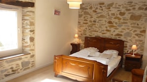 Une chambre avec un lit en bois, des murs en pierre, une fenêtre et deux lampes de chevet.