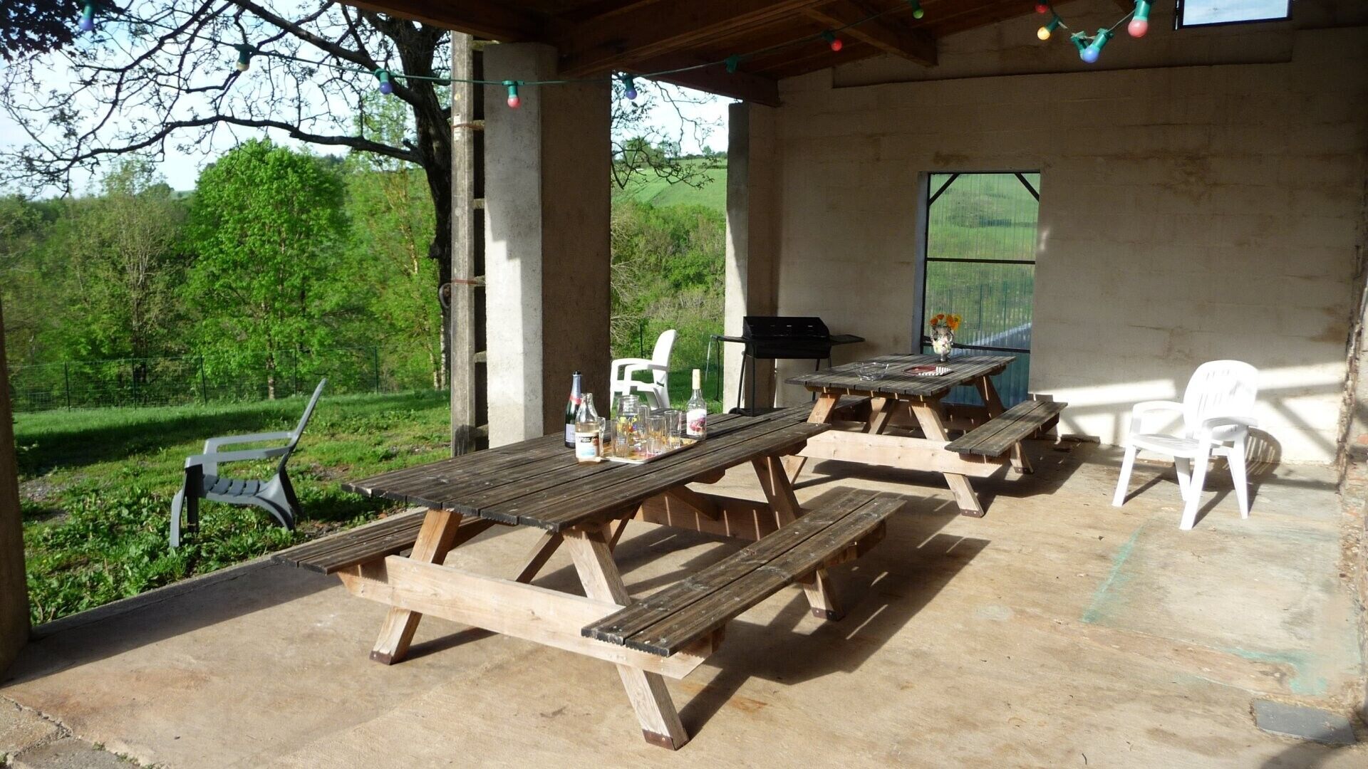 Un patio al aire libre con mesas de picnic, sillas y una parrilla.