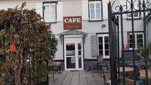 Un café doté d’une terrasse, d’une entrée fermée par un portail et d’une enseigne indiquant qu’il propose des produits de la marque « Couleurs d’Antan ».