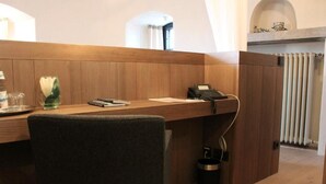 A modern office space with a wooden desk, a telephone, and a vase with a single white flower. - HotelBurg Falkenberg (Falkenberg)