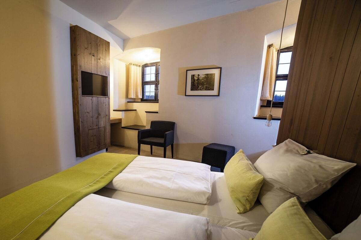 A bedroom with a bed, a chair, a desk, and a window.