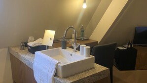 A modern bathroom with a freestanding sink, a towel, a small table with a lamp, and a television. - HotelBurg Falkenberg (Falkenberg)