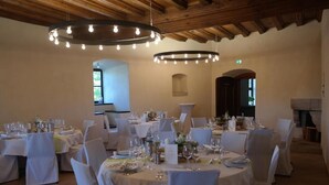 A dining area with round tables set for a meal, white chairs, and hanging light fixtures. - HotelBurg Falkenberg (Falkenberg)