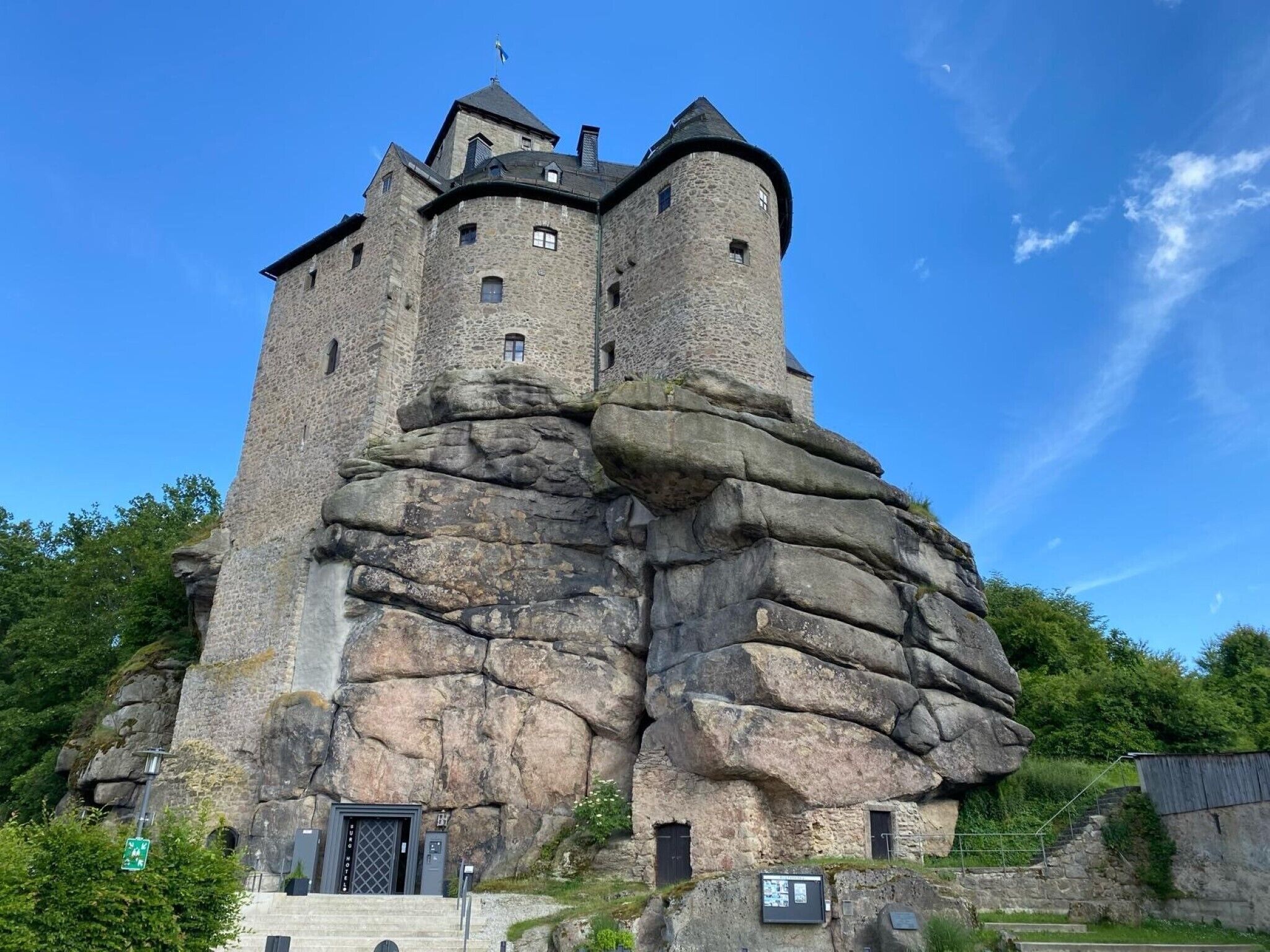 Eine Burg, die in eine große Felsformation eingebaut ist, mit einem Turm und mehreren Fenstern.
