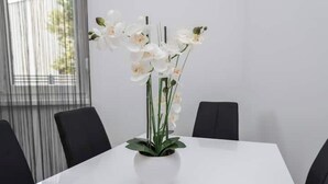 Une table blanche ornée, au centre, d’un arrangement d’orchidées en pot.