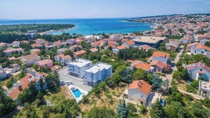 Ett bostadsområde vid kusten med hus, en swimmingpool och utsikt över havet.