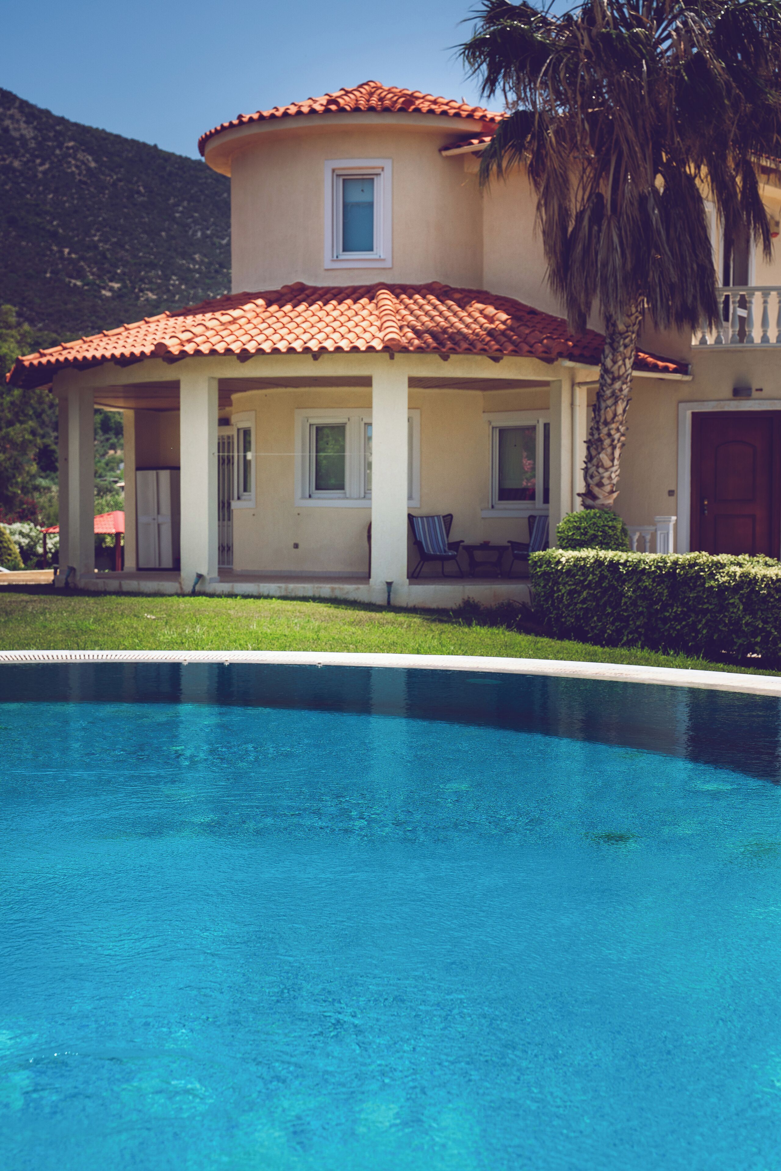 A two-story house with a swimming pool in front.