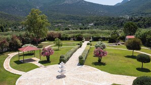 Un jardín ajardinado con un pabellón, césped cuidado y un sendero de piedra que lleva a una fuente.