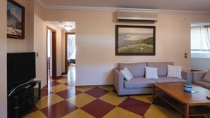 Una sala de estar con piso a cuadros, un sofá, una mesa de centro y un televisor de pantalla plana.