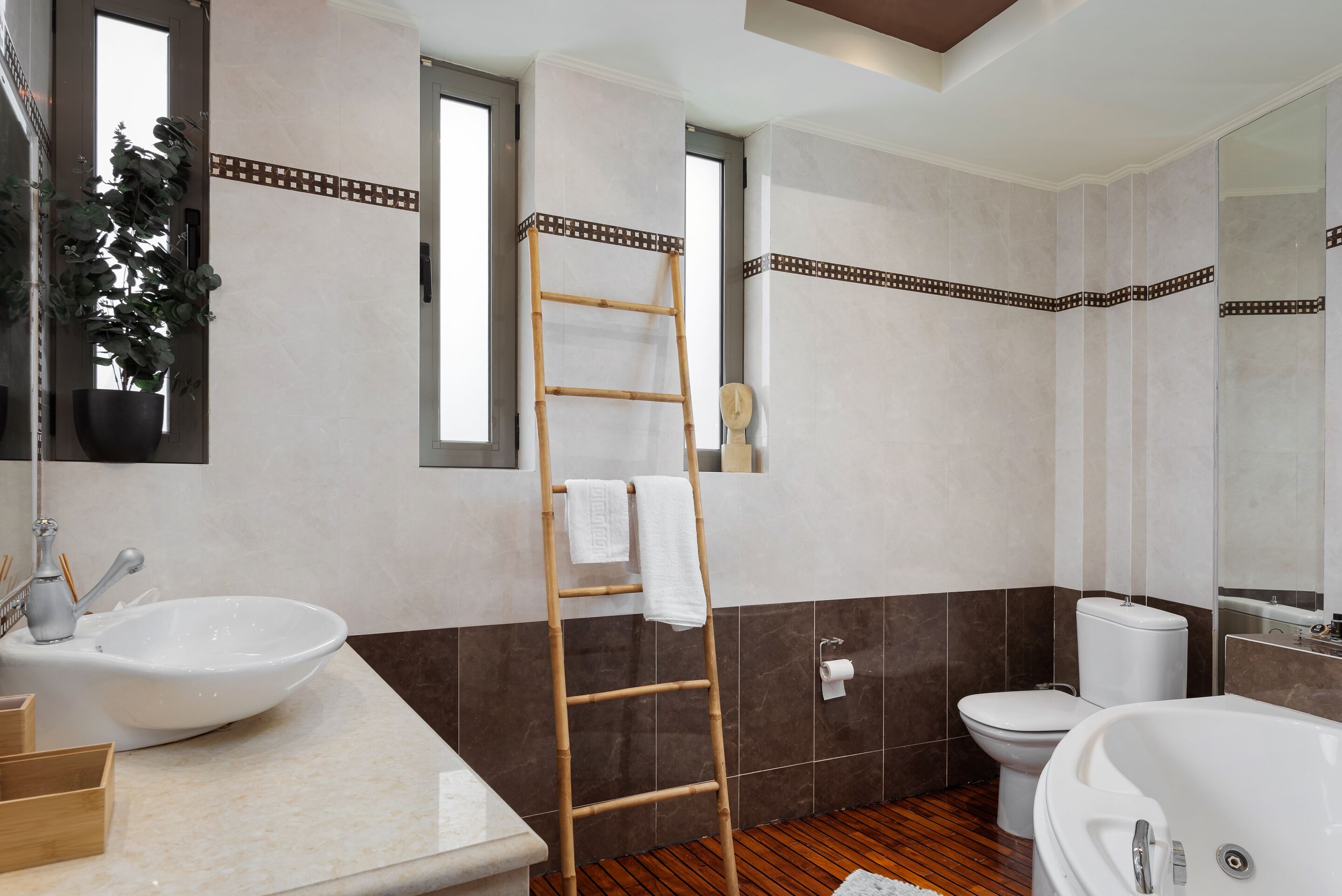 A bathroom with a wooden floor, a white sink, a toilet, and a bathtub.