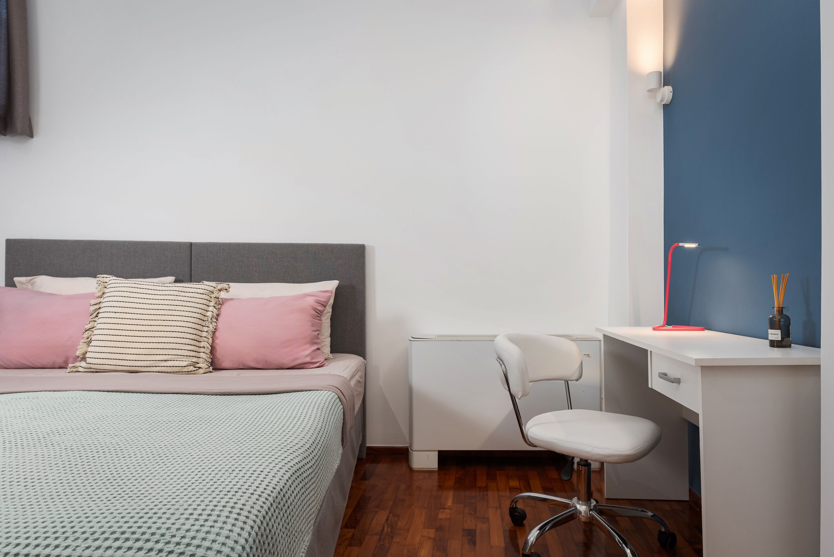 A bedroom with a bed, a desk, and a chair.