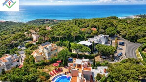 Vista aèria d'una zona residencial costanera amb piscina, diversos edificis i vistes al mar.