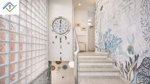Una escala amb un rellotge, plats decoratius i un mural.