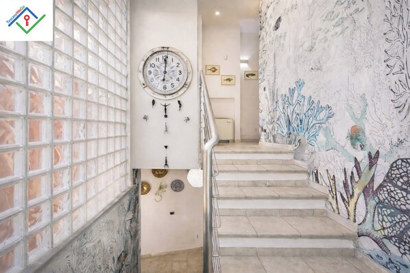 A staircase with a clock, decorative plates, and a mural. - Villa Irene | NEW Luxury Villa with Private Pool, Jacuzzi & Sea View (Chioma)