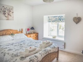 Un dormitorio con cama, mesita de noche, cómoda, ventana con vistas y decoración en la pared.