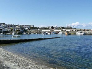 A harbor with boats docked, a clear sky, and buildings in the background. - Tyddyn Gyrfa Cottage (Cemaes Bay)