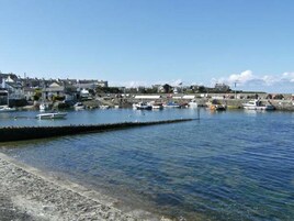 Un puerto con barcos amarrados, cielo despejado y edificios al fondo.