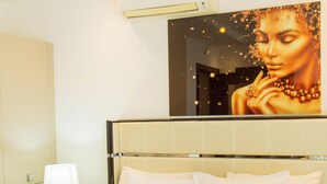 Une chambre d’hôtel avec un grand lit, une table de chevet avec une lampe et un climatiseur fixé au mur.
