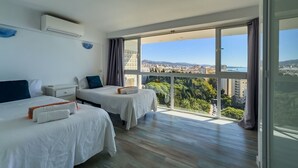 Ein modernes Hotelzimmer mit zwei Betten, einem großen Balkon und Blick auf die Stadt.