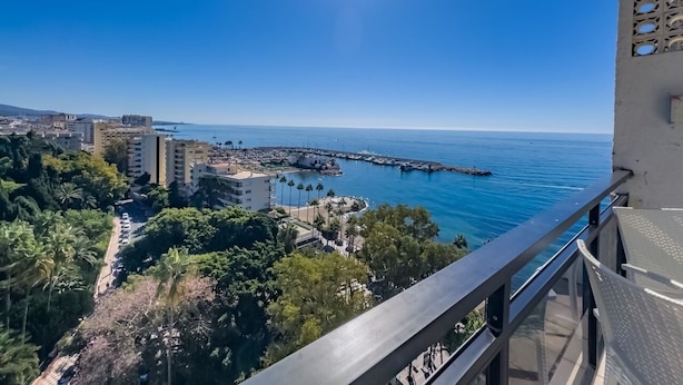 Ein Balkon mit freiem Blick auf eine Küstenstadt, einschließlich Gebäude, einem Steg und dem Meer.
