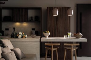 Eine moderne Küche mit einer zentralen Kochinsel, Holzbarhocker, Pendelleuchten und einer dekorativen Vase mit Blumen.