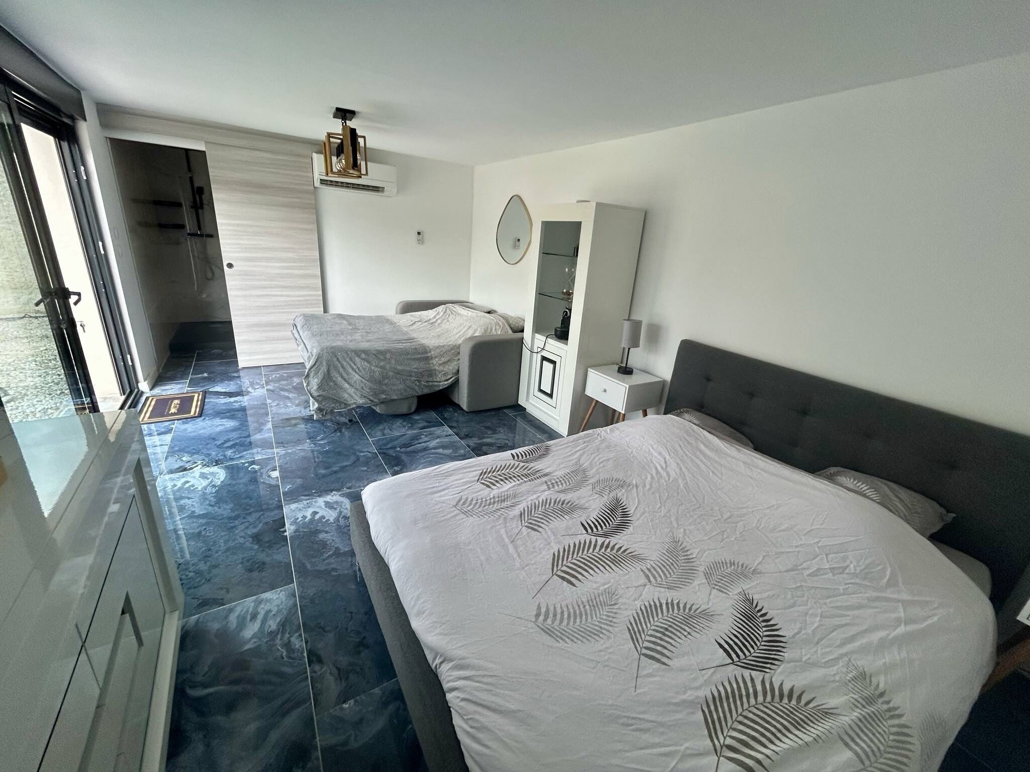 Une chambre moderne avec un grand lit, un plus petit lit, une coiffeuse et un miroir.