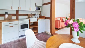 Uma cozinha compacta com armários brancos, bancada de madeira e um espaço de jantar com mesa e cadeira.